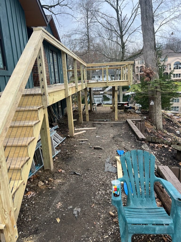 Wooden deck construction by a lake; stairs lead to upper level.