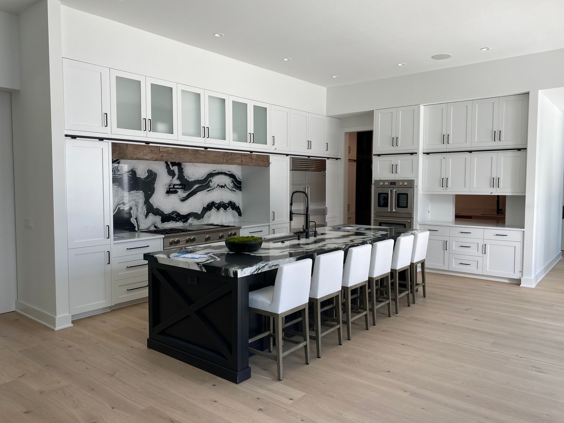 Modern kitchen with a black and white island, white cabinets, and light wood floors.