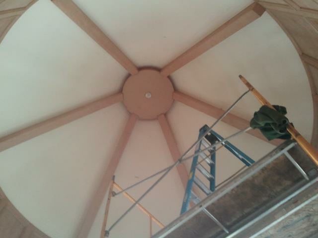 Wooden ceiling with radial beams, light-colored paint, and scaffolding.