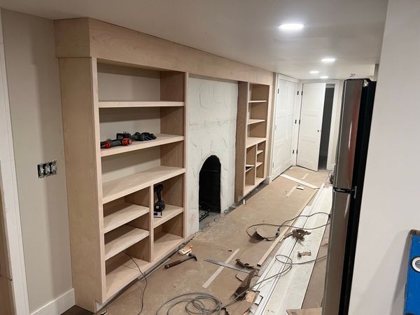 Unfinished built-in shelving and fireplace surround in a room under construction; neutral tones.
