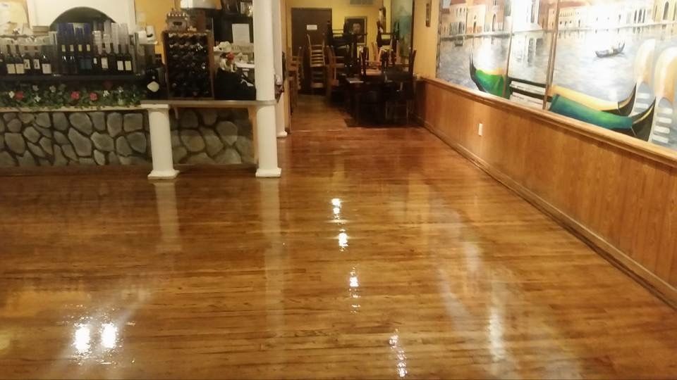 Shiny wooden floor in an Italian restaurant; walls feature stone and a mural of gondolas.