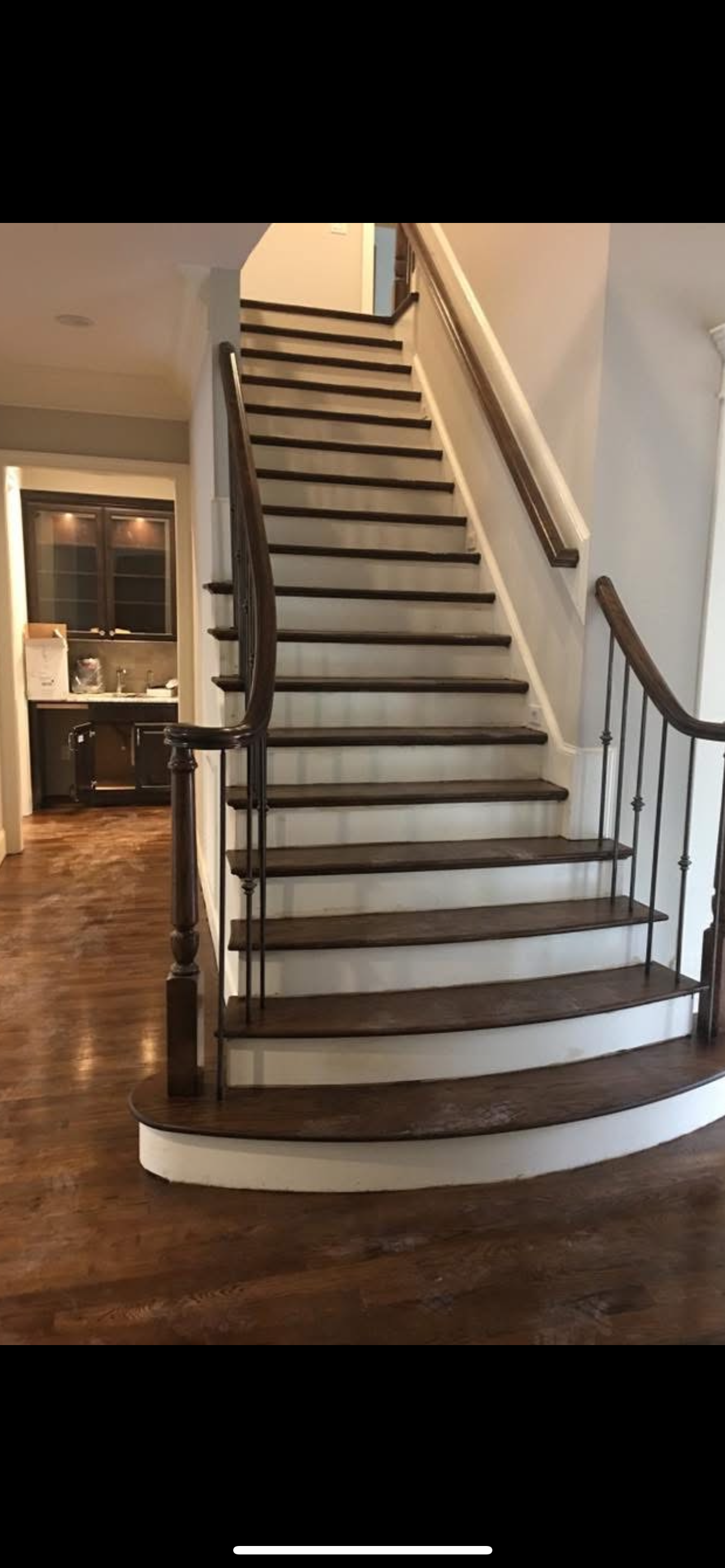 A wooden staircase with dark steps, white risers, and a curved handrail in a home.