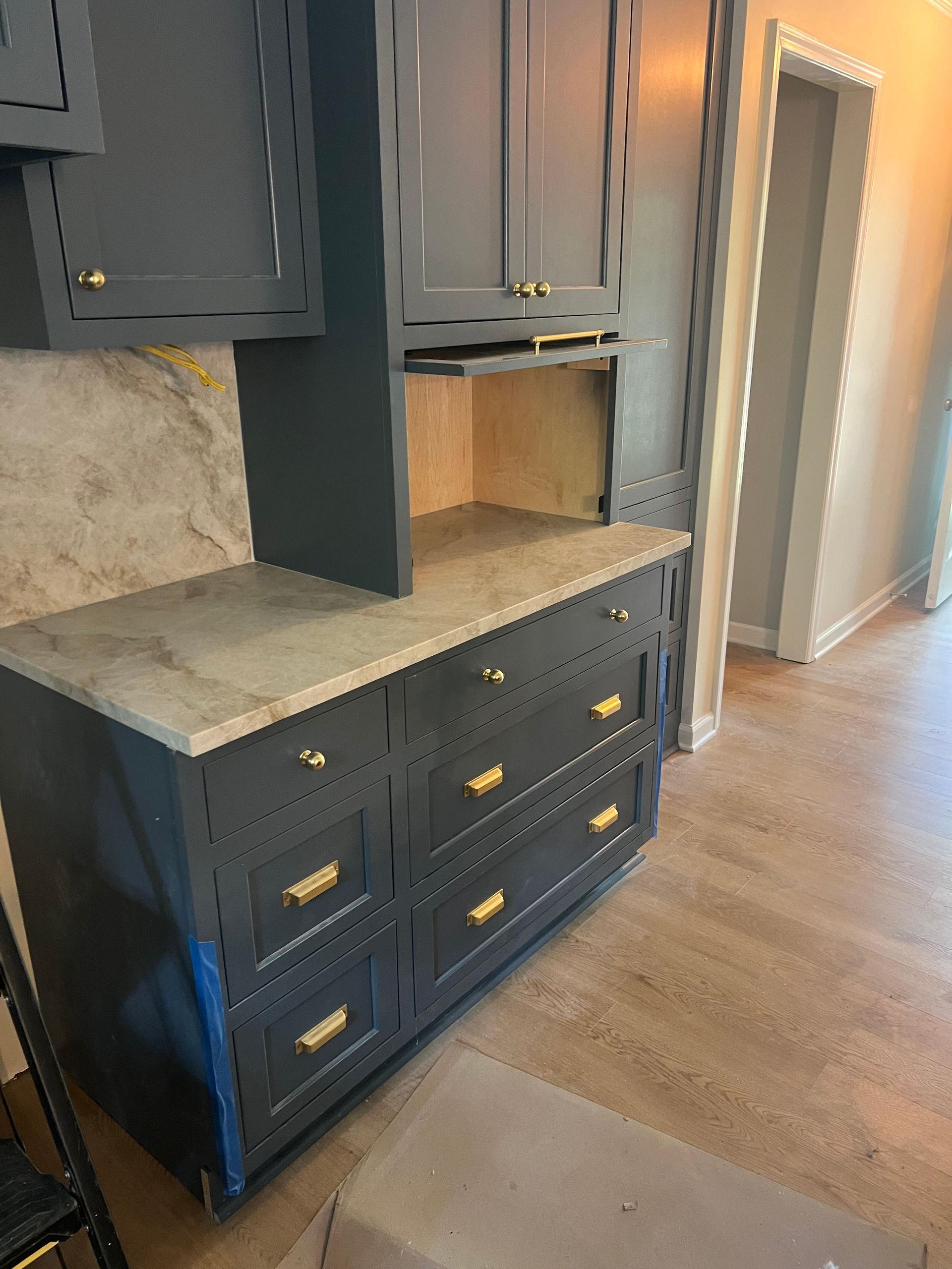 Dark gray kitchen cabinets with gold hardware and a light countertop.