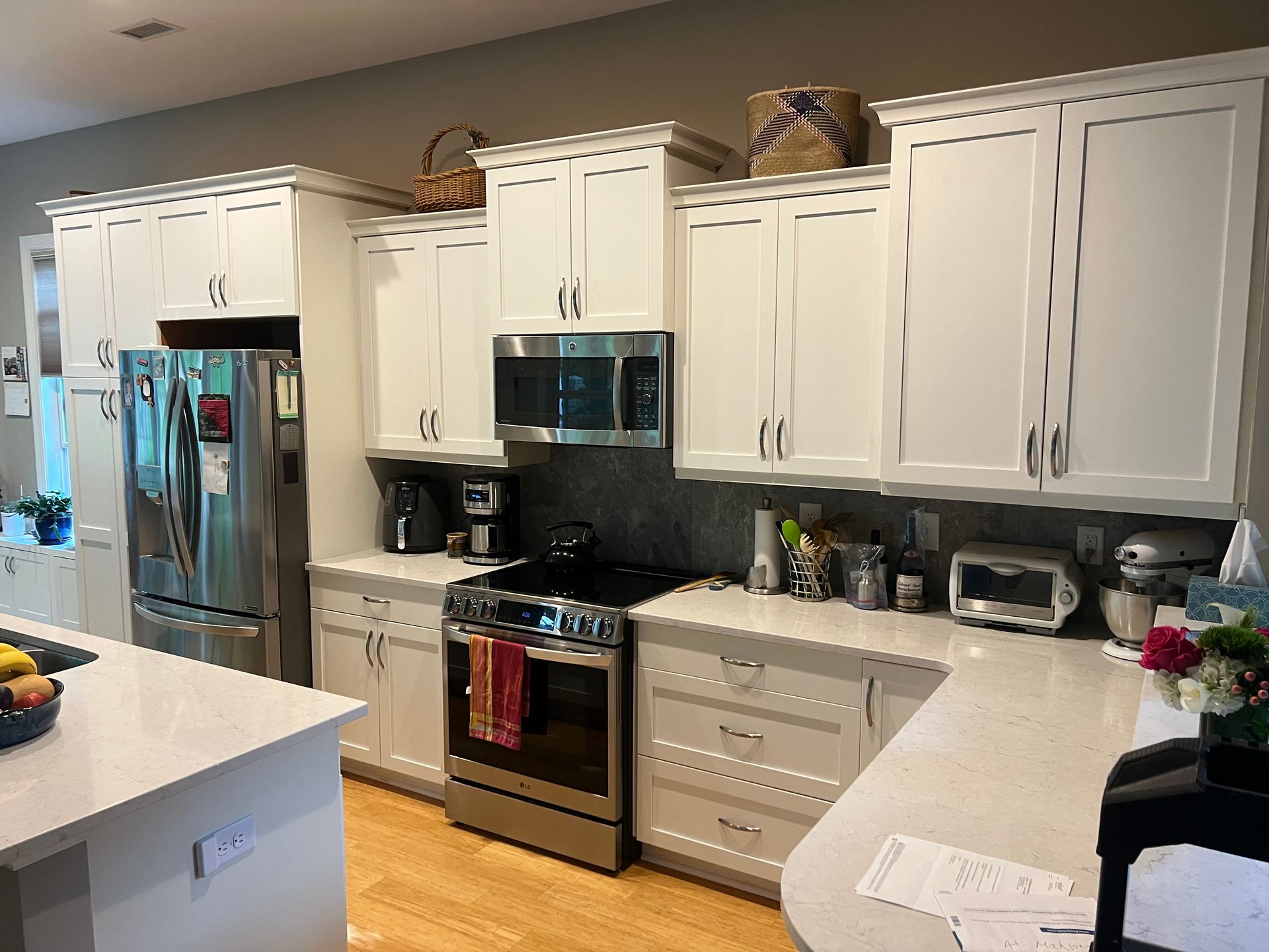 White kitchen with stainless steel appliances, white cabinets, and light countertops.