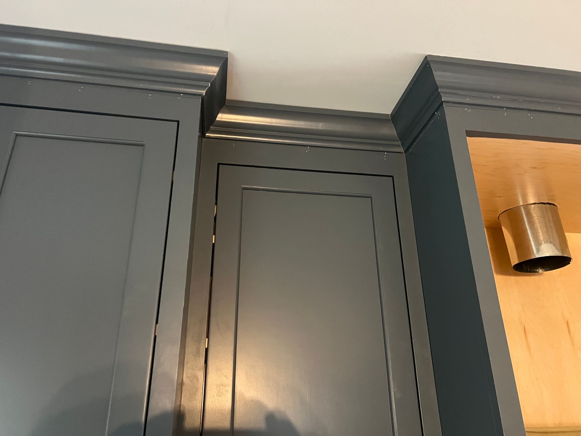 Gray kitchen cabinets with crown molding against a white ceiling.