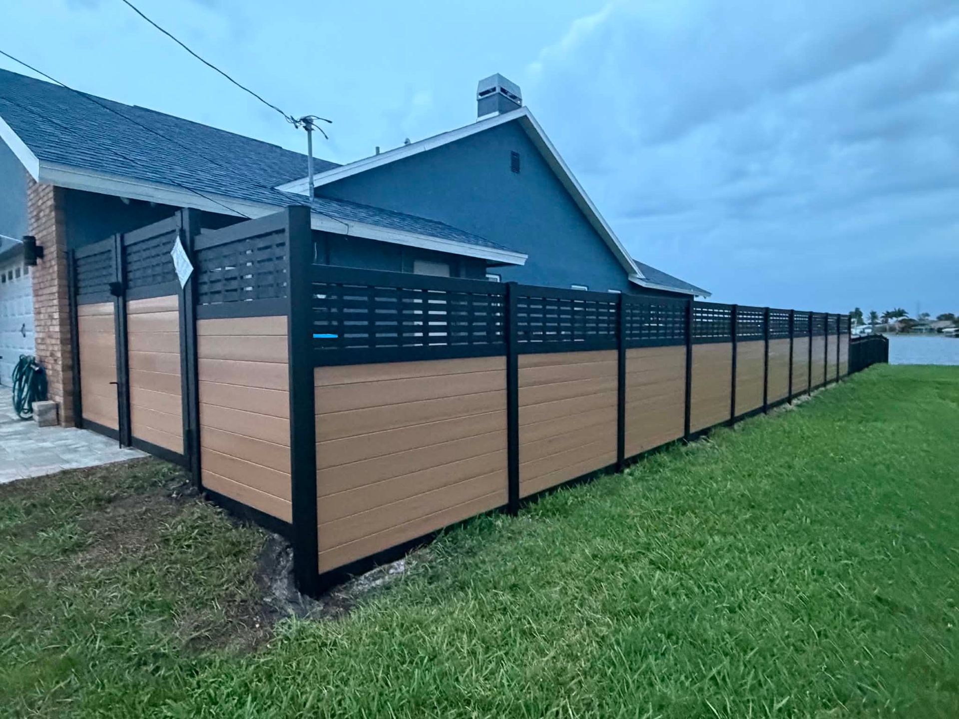A white vinyl fence is sitting in the middle of a dirt field.