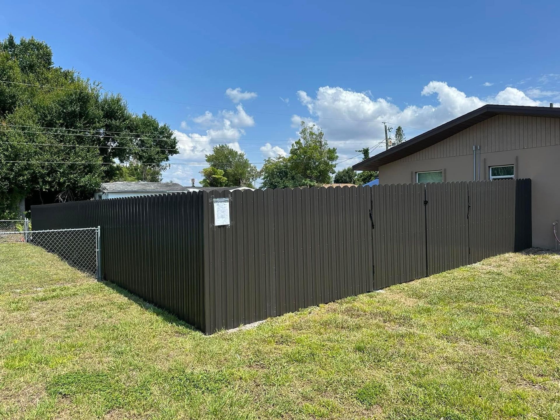 A black aluminum fence surrounds a lush green field.