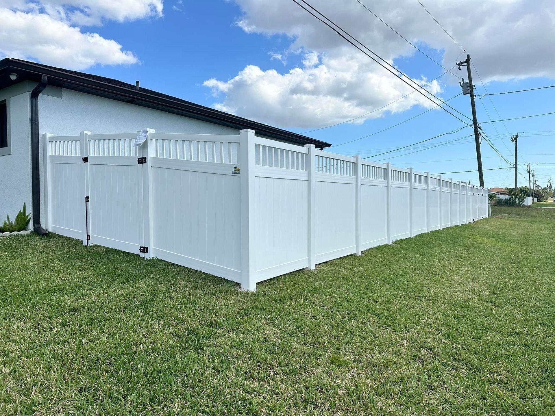 A white fence is sitting in the grass in front of a house.