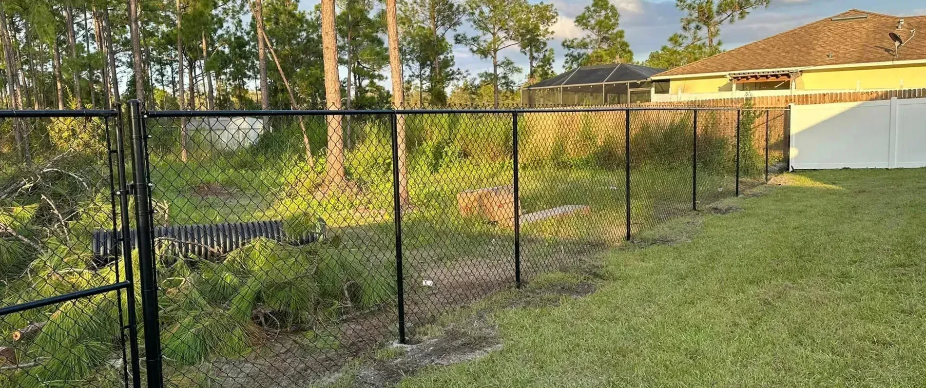 A chain link fence is sitting in the middle of a lush green field.