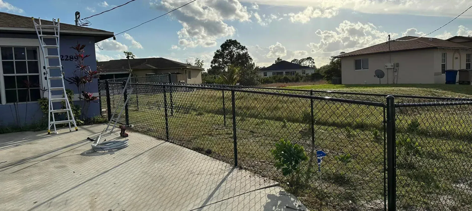 A chain link fence is being repaired in front of a house.