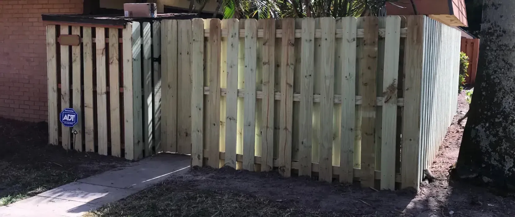 A wooden fence with a gate in front of a house.
