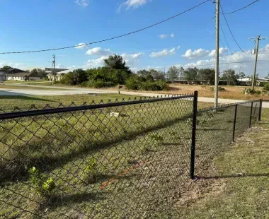 A chain link fence is surrounding a grassy field.