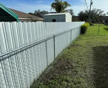 A white chain link fence surrounds a lush green yard.