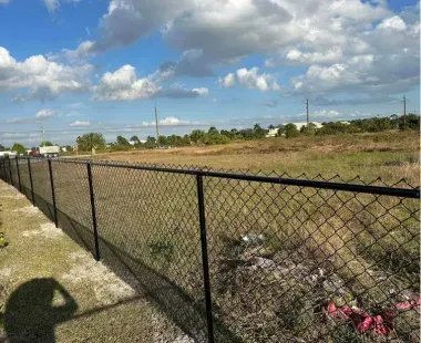 A chain link fence surrounds a large field.