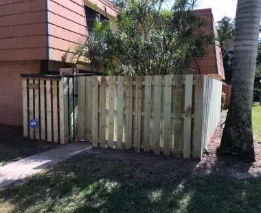 A wooden fence is in front of a brick building.
