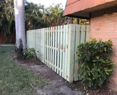 A wooden fence is sitting next to a brick building.