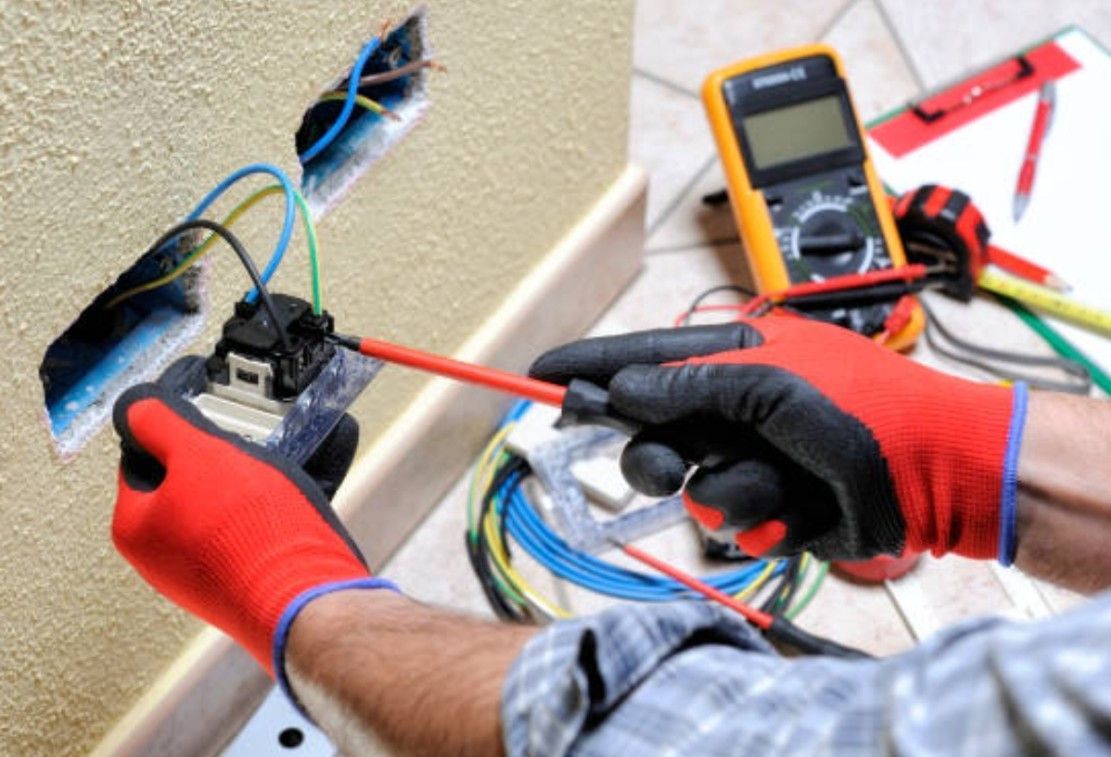 A professional uses a multimeter to test electrical components inside an open boiler control panel.