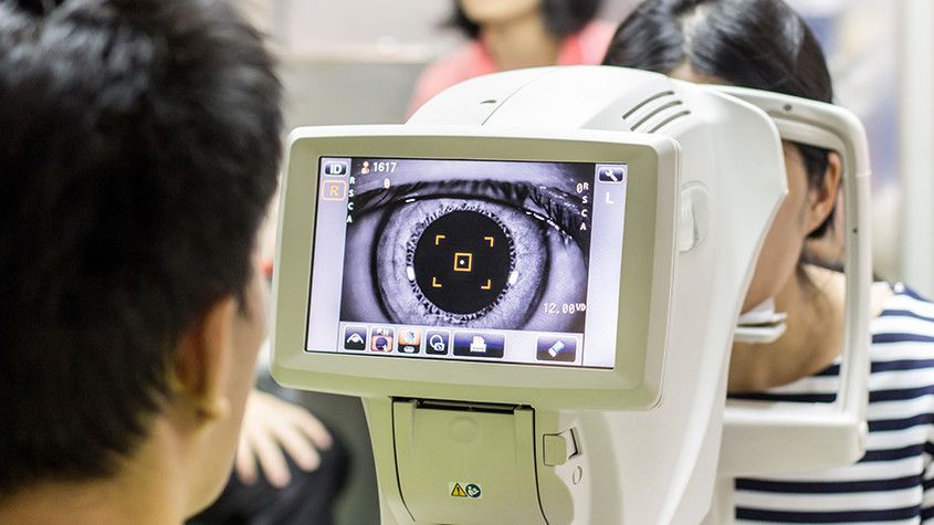 Person using a medical eye-scanning device with a screen showing a close-up of an eye