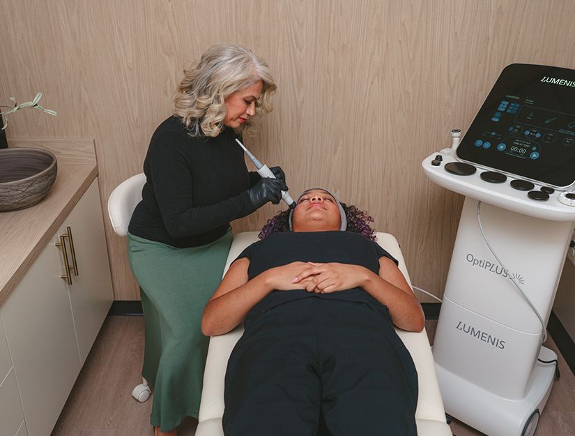 Doctor examining patient in a clinic room beside a medical imaging machine