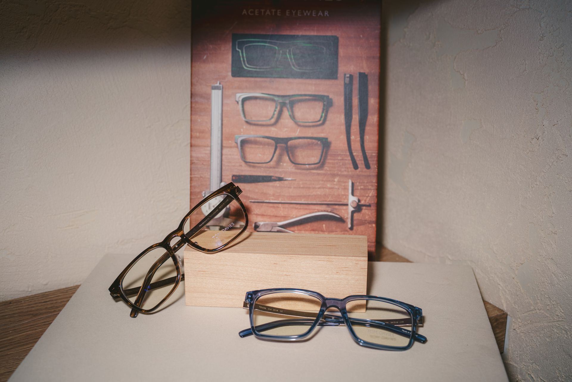 Eyeglasses displayed beside a portrait poster of a woman with red-tinted light on her face