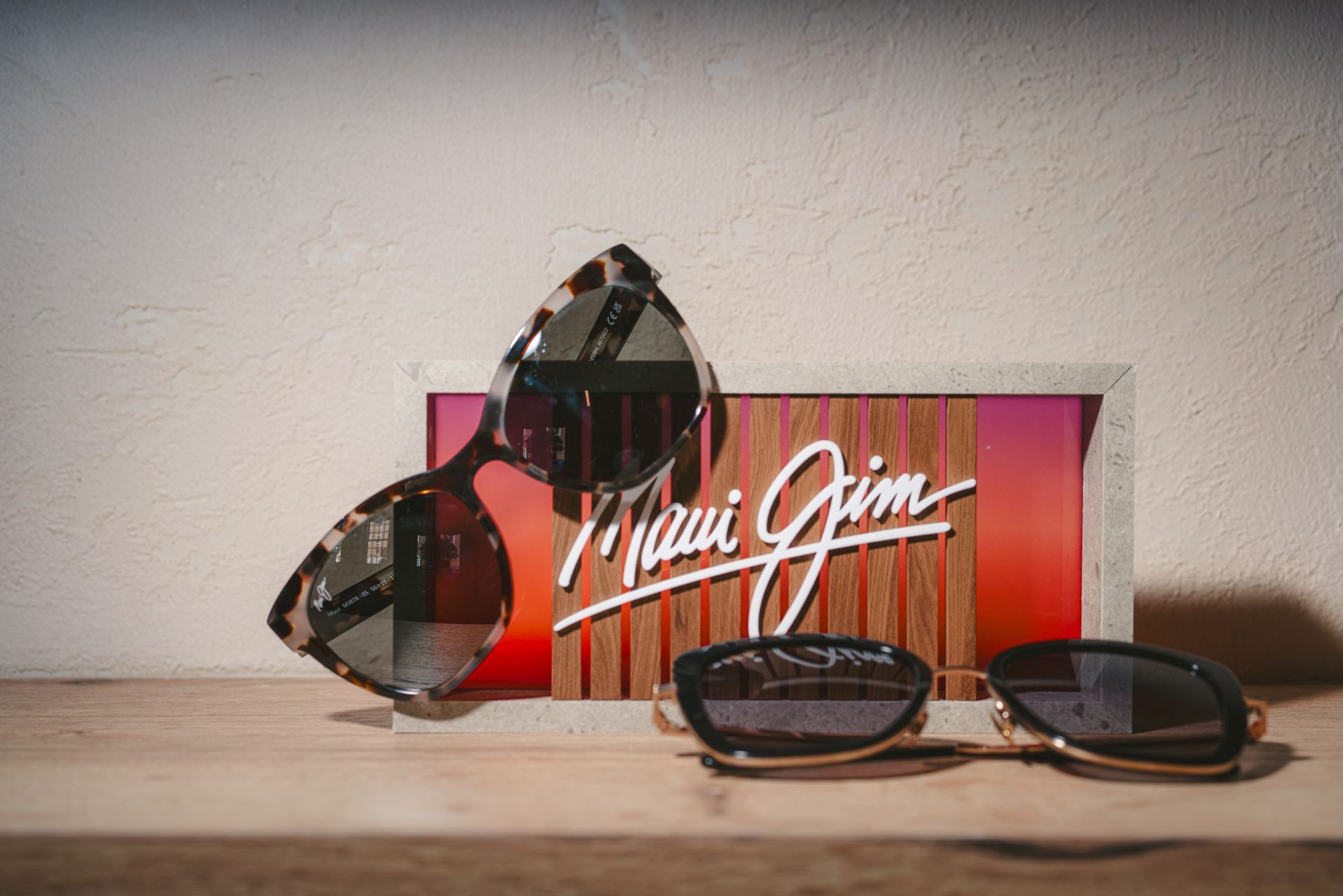 Sunglasses displayed before a red Maui Jim box on a tabletop against a light wall