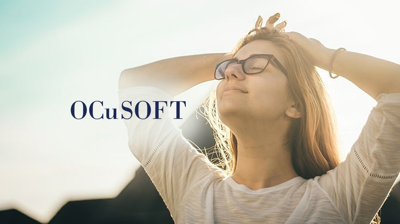 Woman in glasses enjoying sunlight beside the OCuSOFT logo