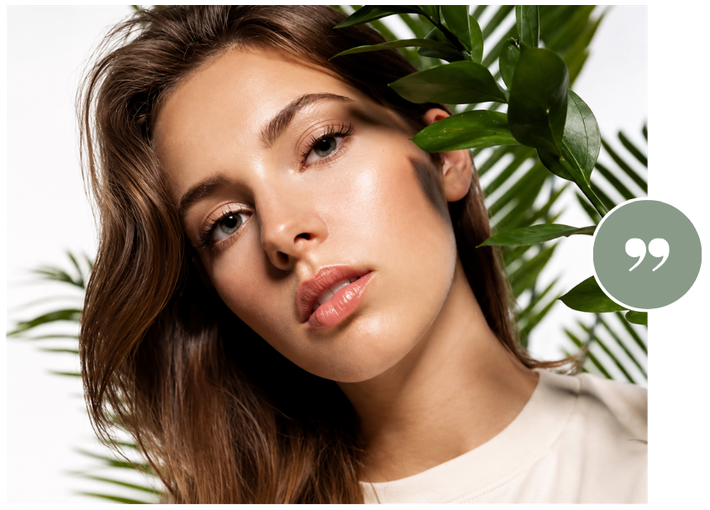 Portrait of a person with wavy hair beside green leaves, looking at the camera