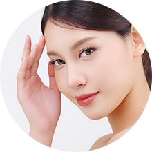 Portrait of a woman gently touching her face, with a soft smile and natural makeup.