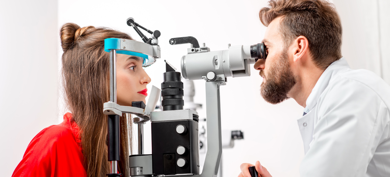 Optometrist examining a woman with an eye chart machine in a clinic