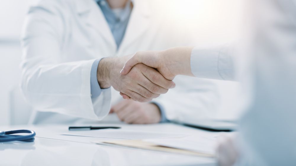 Doctor shaking hands with a patient in a bright medical office