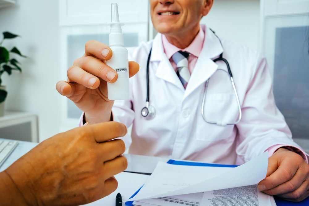 Doctor in white coat handing medicine to a patient in a clinic office.