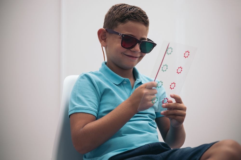 Boy in sunglasses examining a card with red symbols while sitting on a white couch