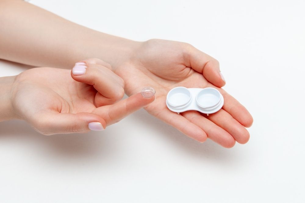 Hands holding and pouring white pills from a pill organizer onto an open palm