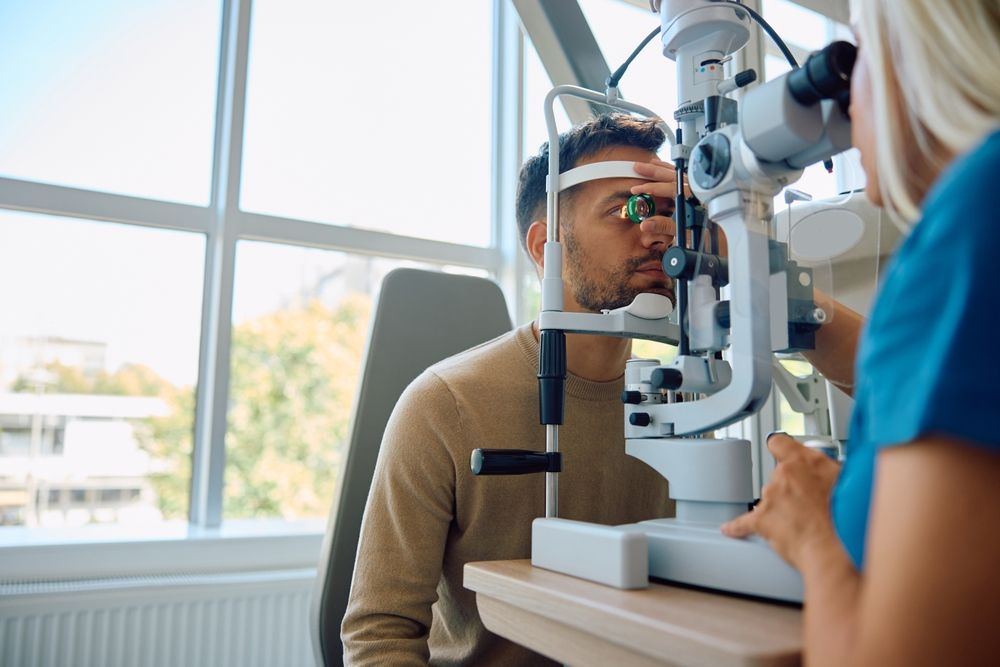 Eye exam at an optometrist: patient in a chin rest while doctor adjusts a slit lamp.