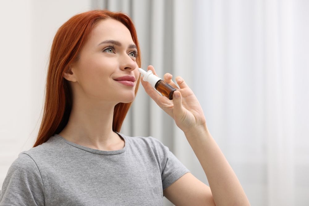Woman applying makeup with a brush in a bright room