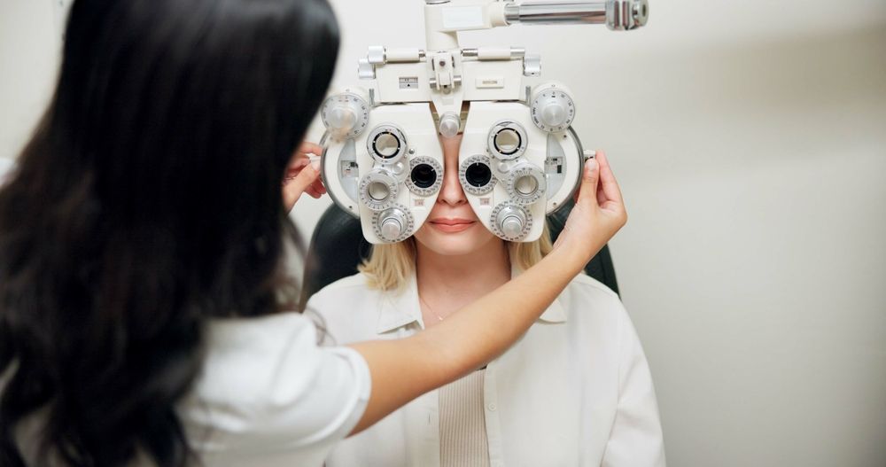 Optometrist adjusting phoropter on patient during eye exam in a clinic