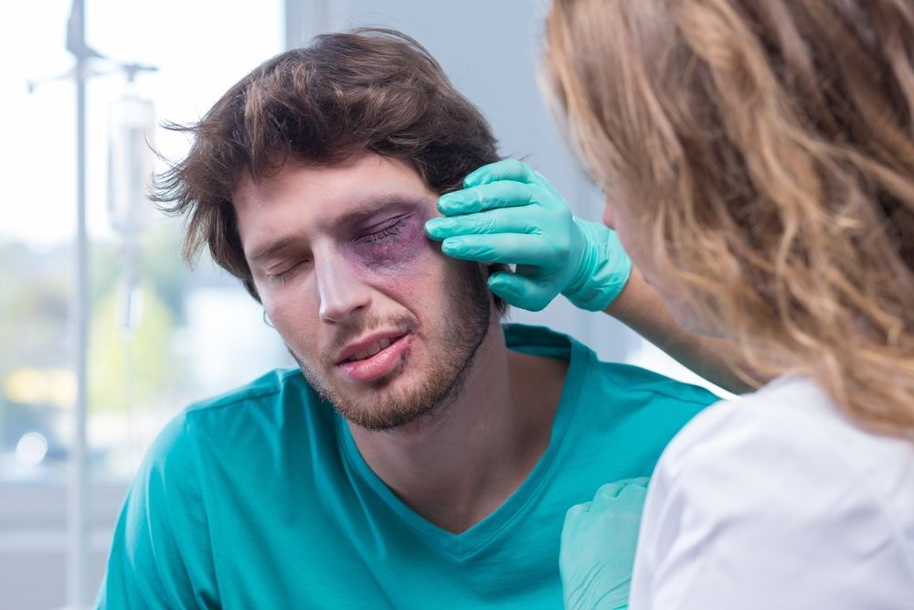 Healthcare worker applying a cold compress to a man's swollen eye in a clinic