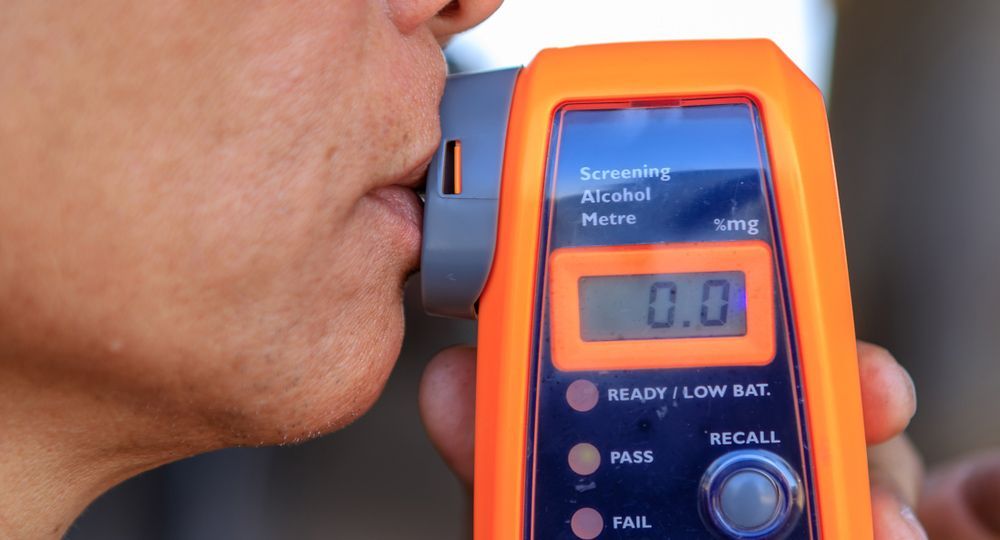 A Woman Blowing In Alcohol Testing Device — Tim Warren Auto Airconditioning & Electrical In Bowen, QLD