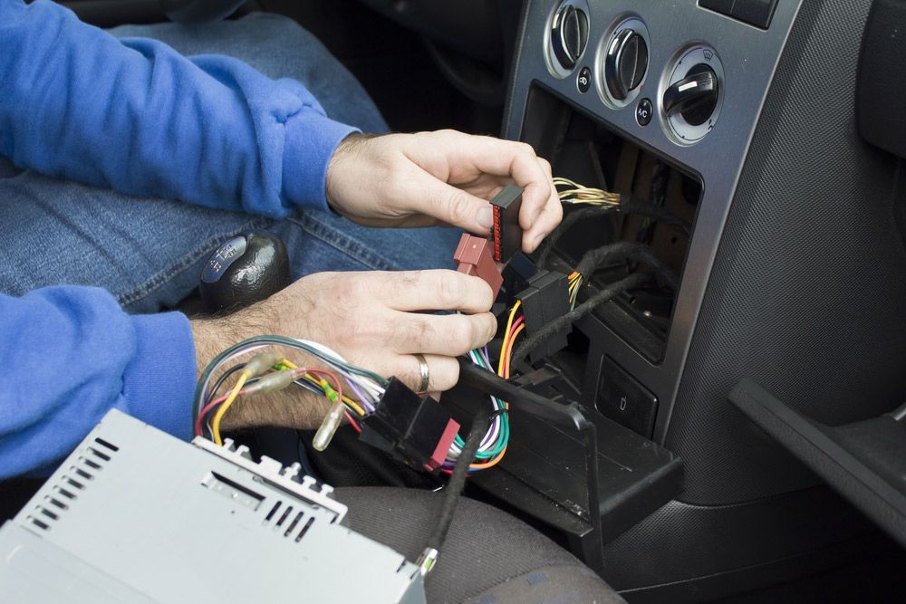 A Man Is Installing A Car Radio In A Car — Tim Warren Auto Airconditioning & Electrical In Bowen, QLD 