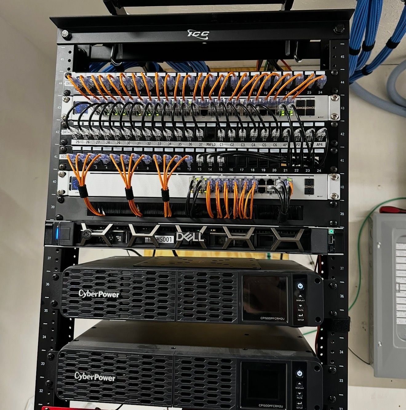 Network rack with patch panels, orange and black cables, and two Dell servers in a server room