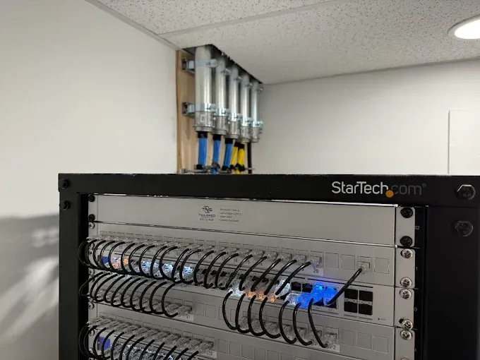 Server rack with patch panel and blue network cables in a white room