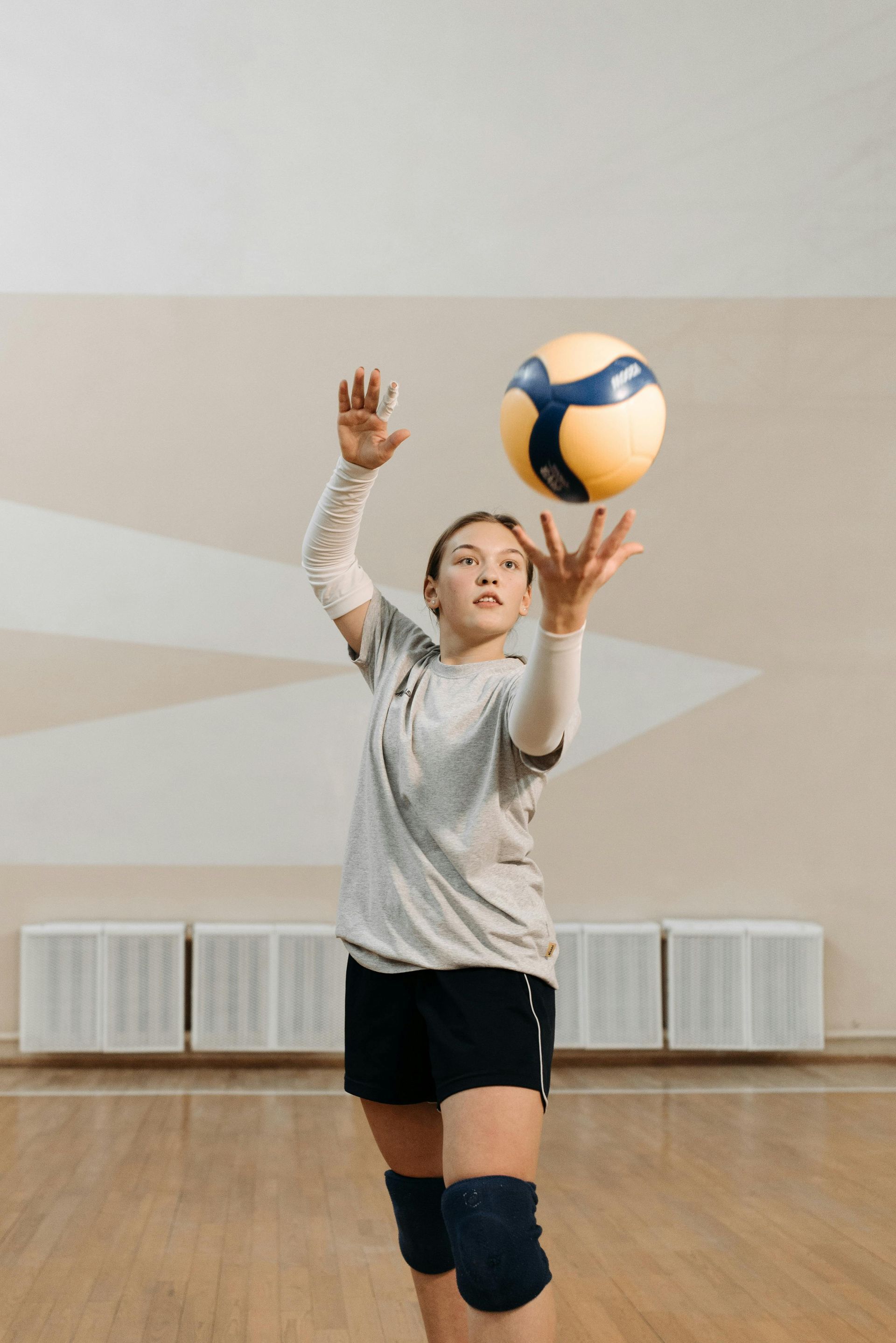 A young girl is playing volleyball in a gym.
