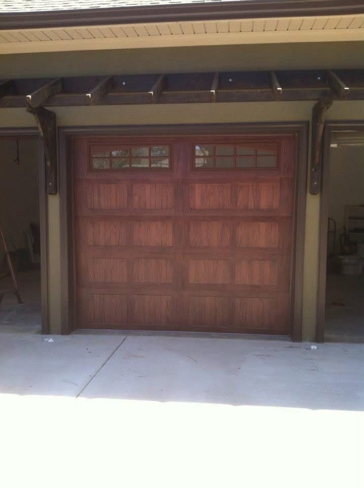 Wooden garage door with dark trim under a covered driveway