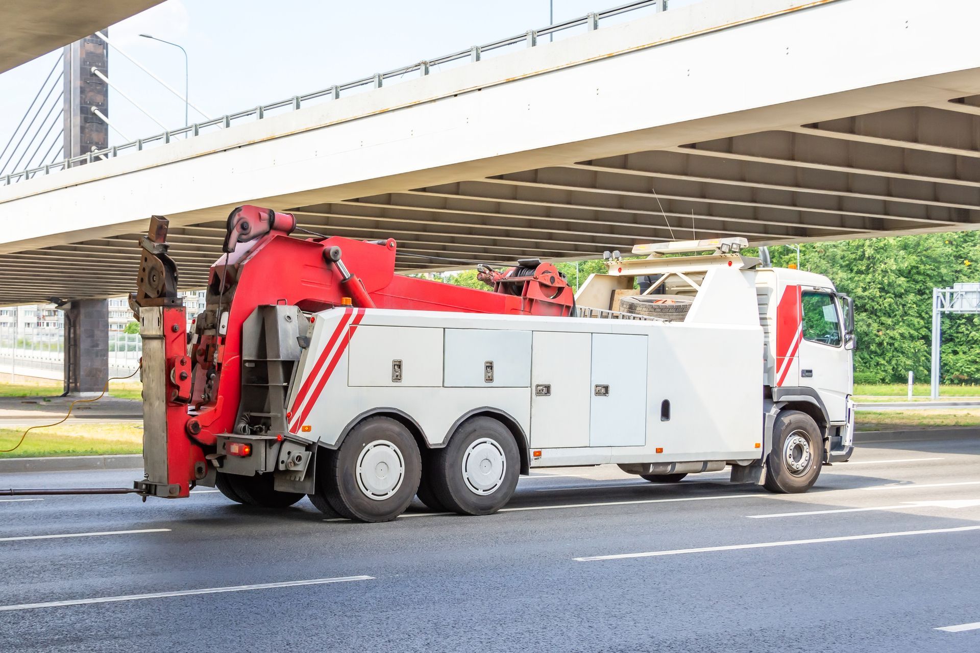 Semi truck towing service vehicle on a highway under a bridge