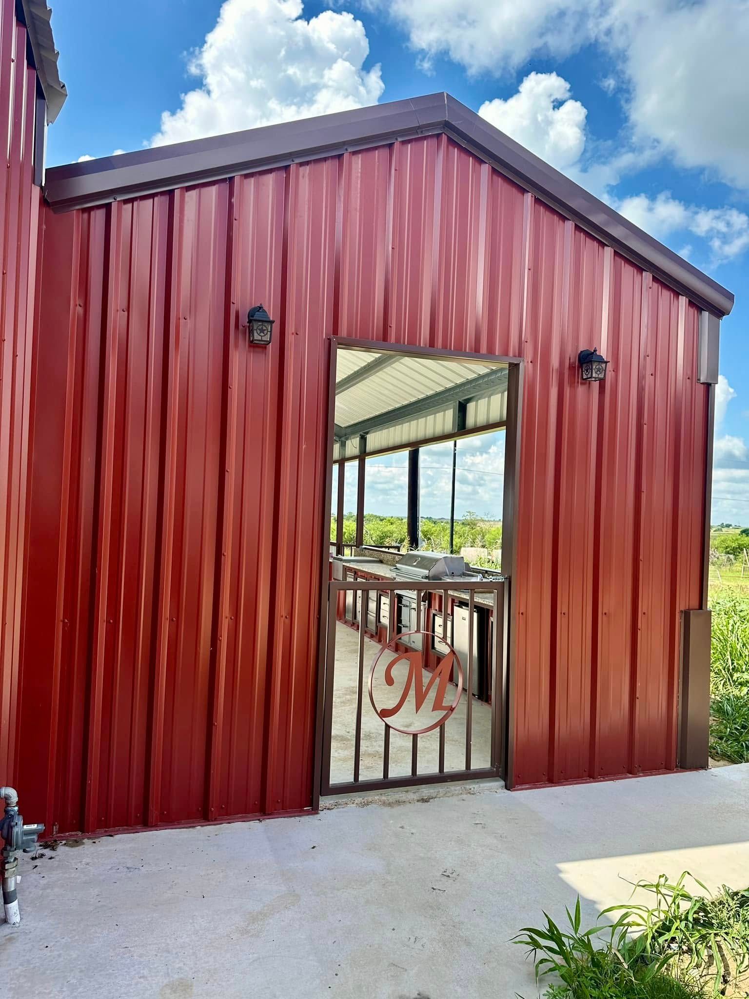 Red metal building with an open doorway leading to a patio; sunny day.