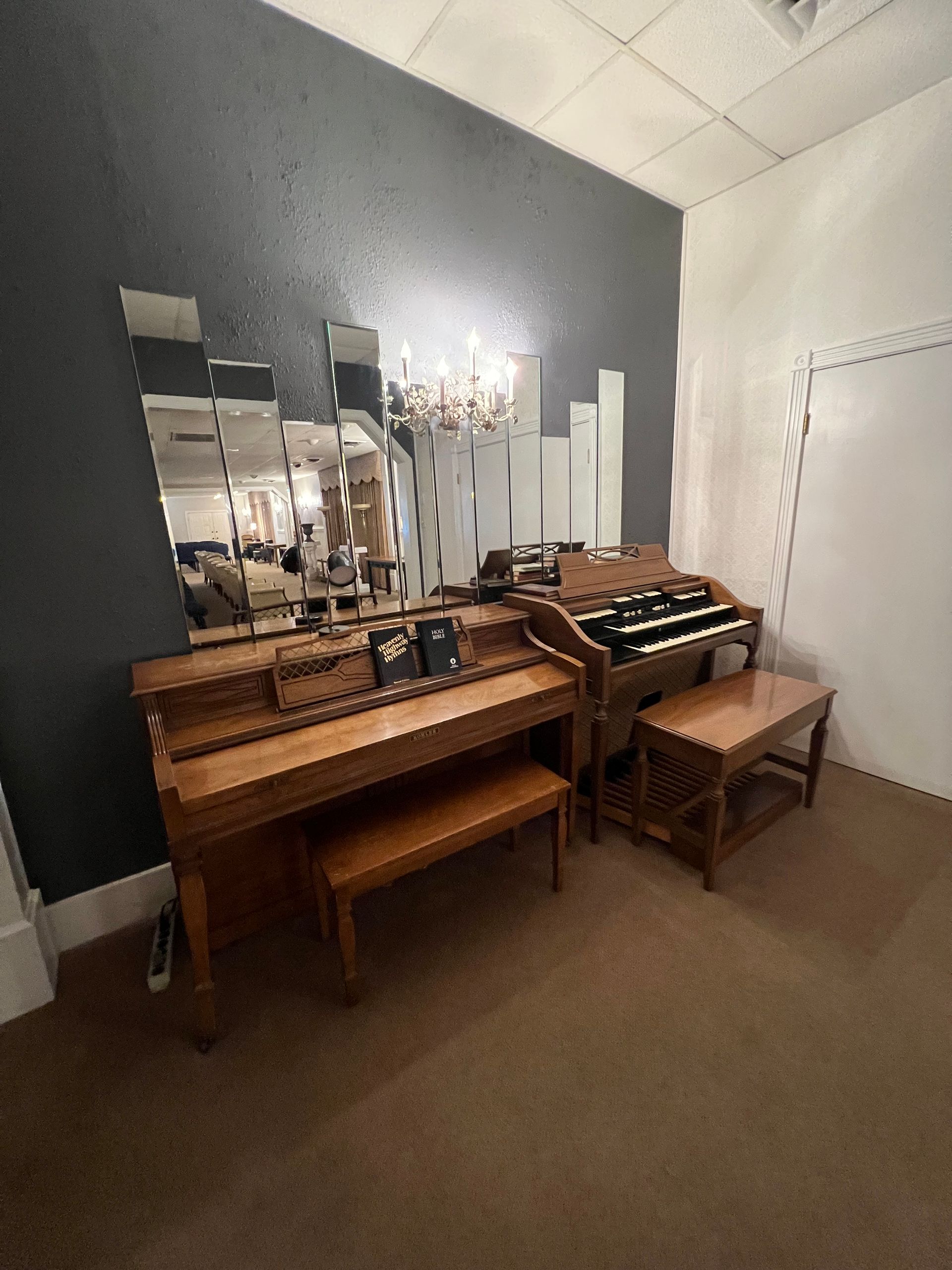 Vintage vanity table with mirror, chandelier, and bench in a room with dark accent wall.