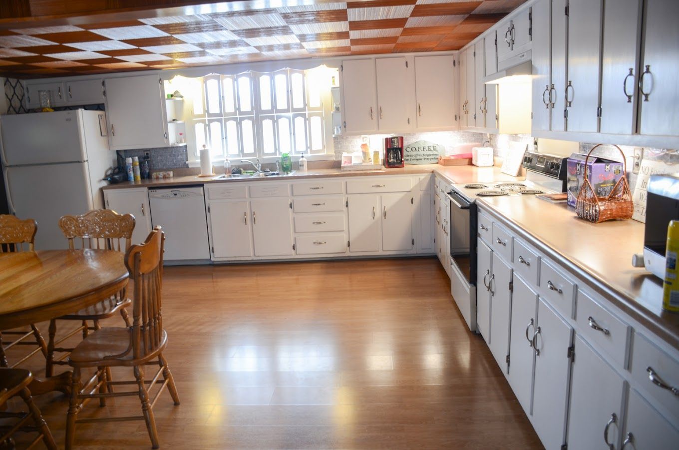 Bright kitchen with white cabinets, wood floor, and dining table near a window