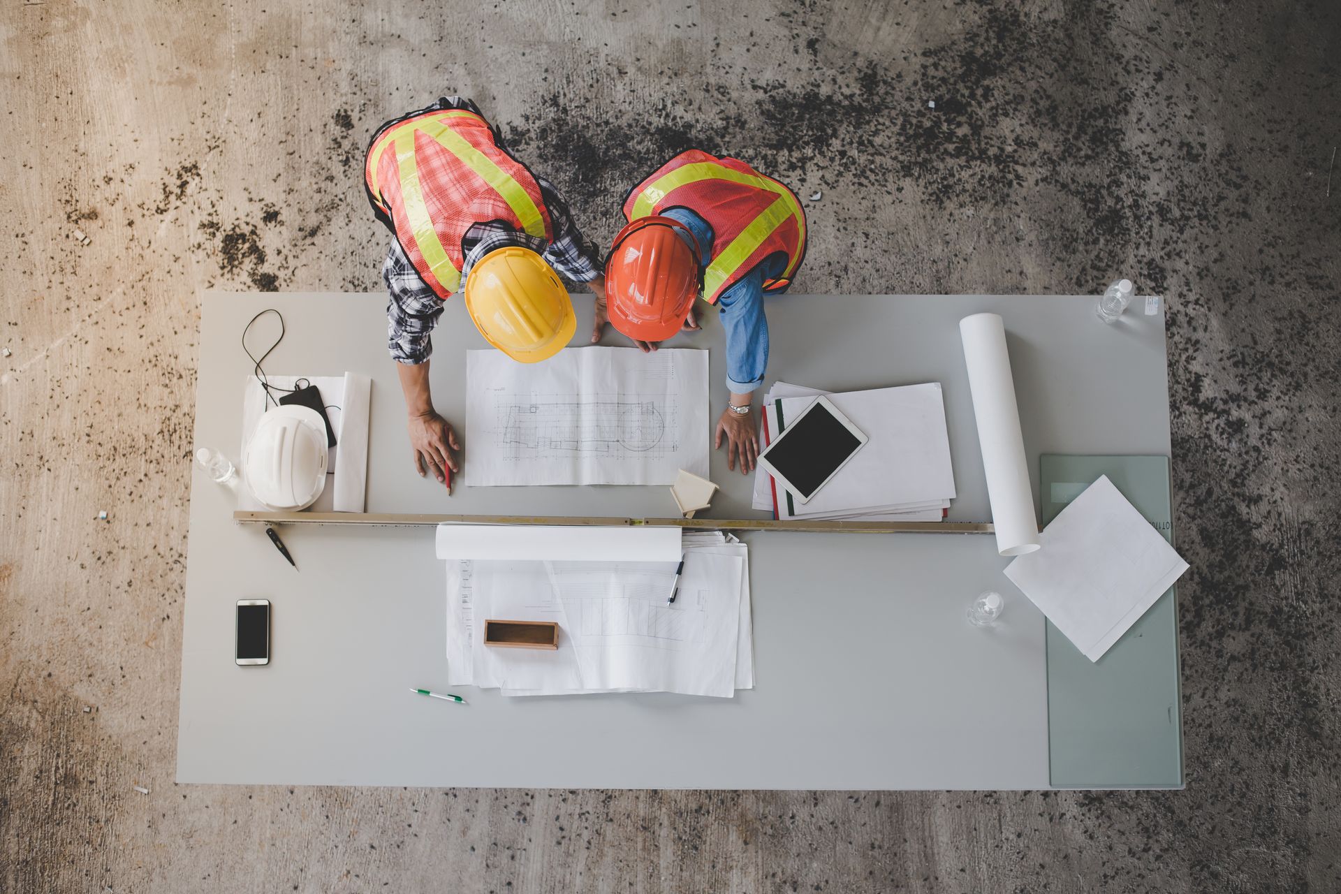 Deux ouvriers du bâtiment regardent un plan sur une table.