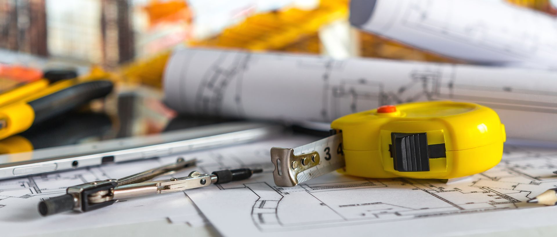 Un ruban à mesurer jaune est posé sur un plan sur une table.