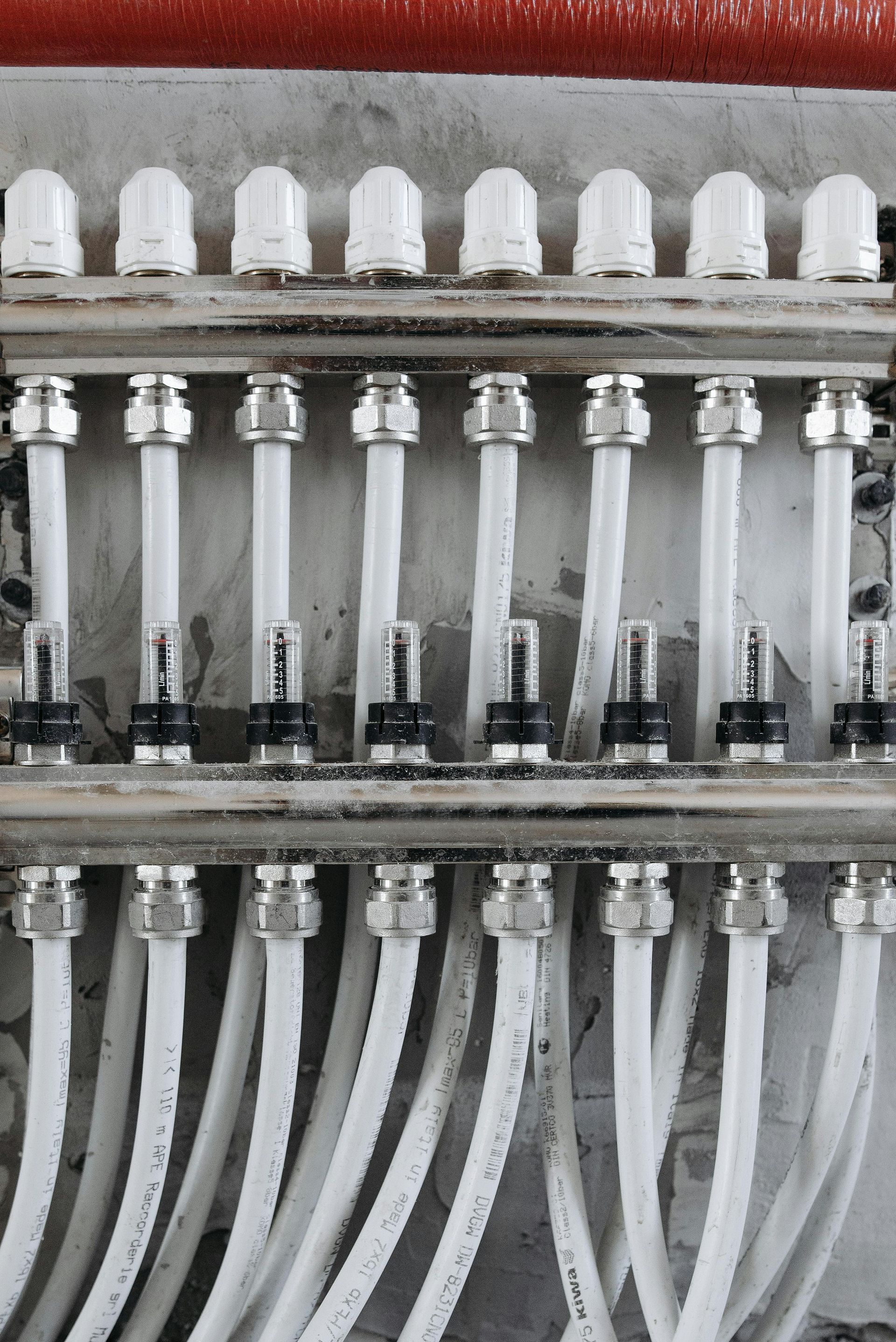 White and silver pipes connected to a manifold in a concrete setting.